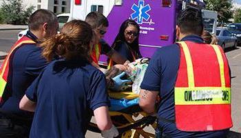 一群学生带着训练假人躺在救护车旁边的担架上. 太阳集团娱乐场登陆网站应用科学护理副学士学位.